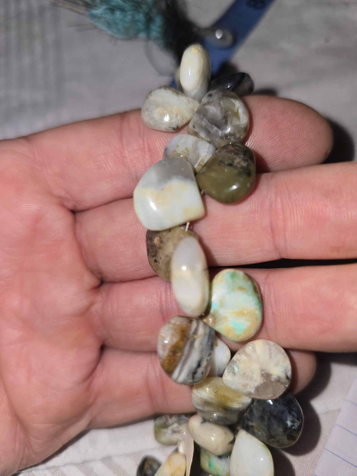 White mottled opal teardrop beads in hand