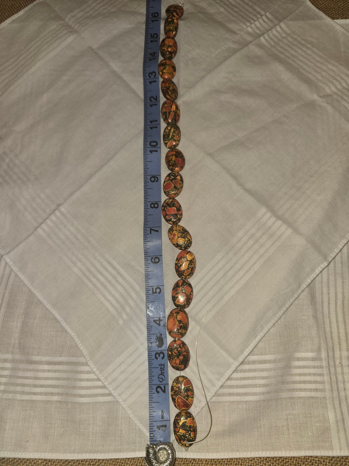 Picasso Jasper oval bead strand, orange black mosaic, 17 beads, 16 inches, with ruler for scale