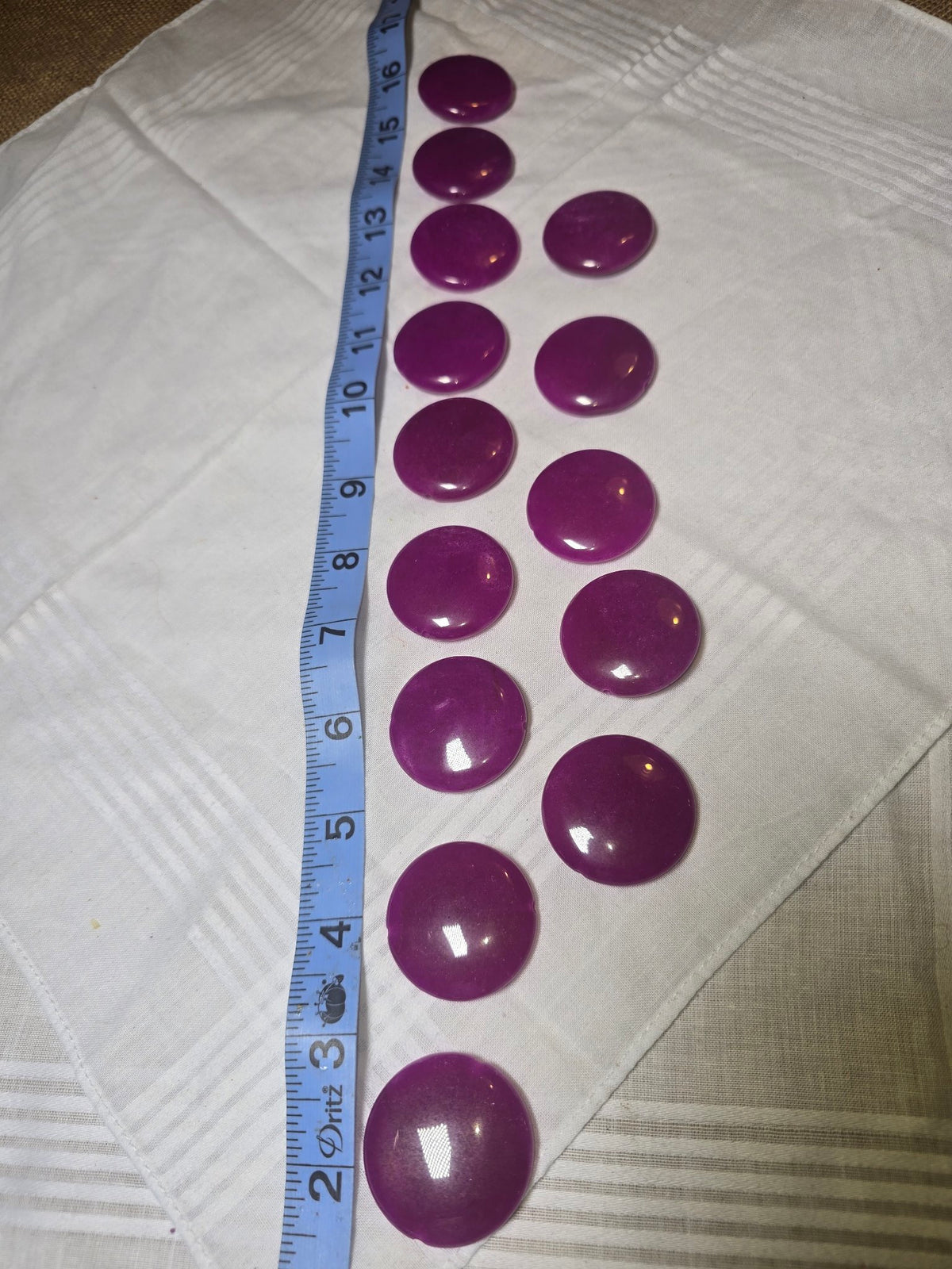 Set of 14 large purple jade coin beads laid out with ruler for scale