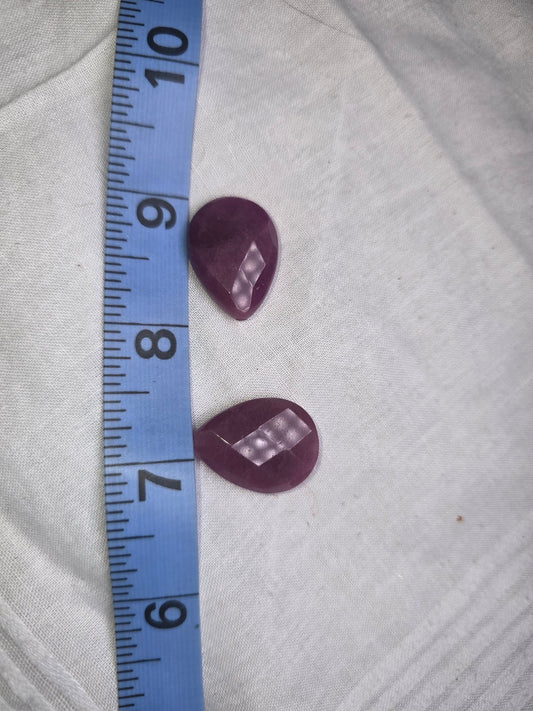 Two raspberry pink-red faceted teardrop beads with ruler for scale