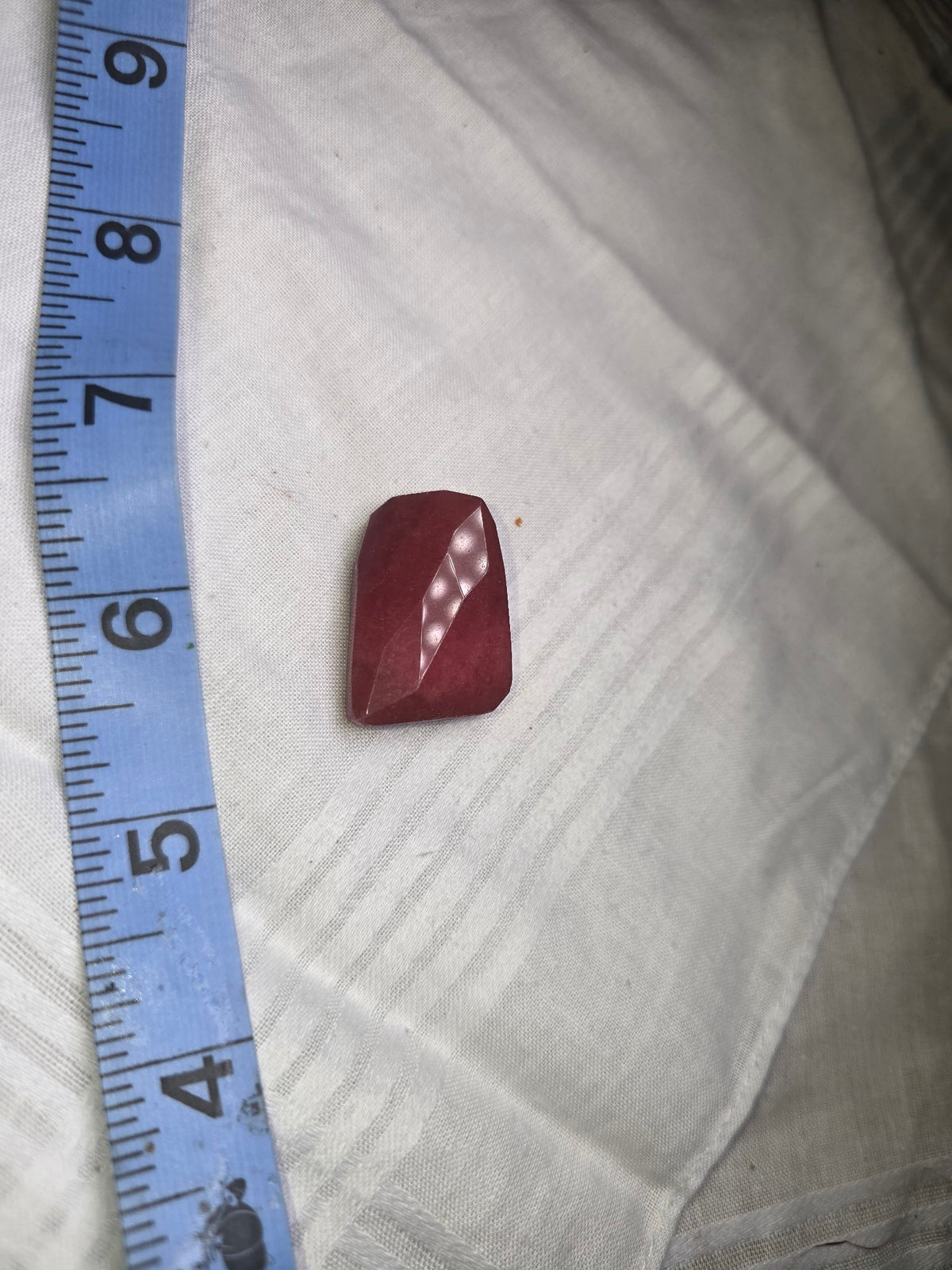 One deep raspberry red faceted rectangle bead with ruler for scale