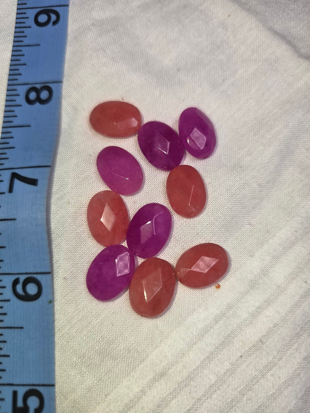 Mixed magenta-purple and peach faceted oval beads with ruler for scale