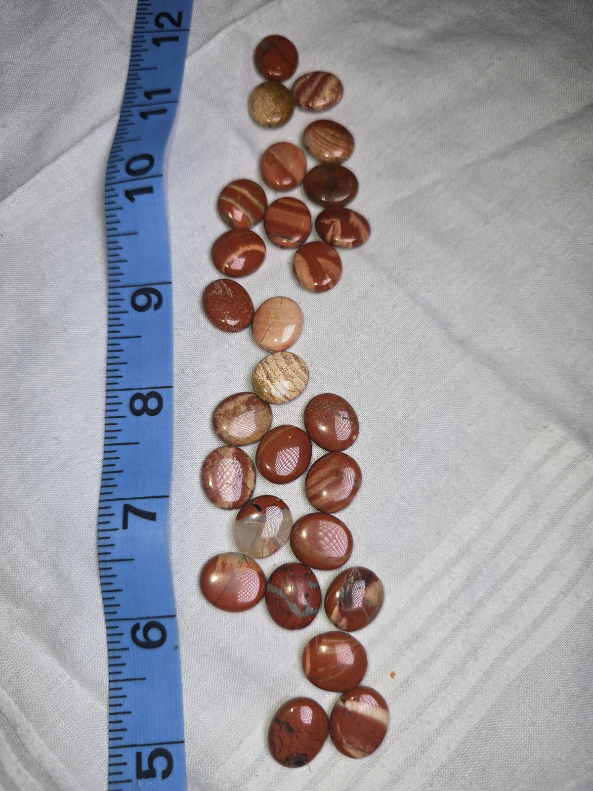 Red jasper flat oval drilled beads with ruler for scale