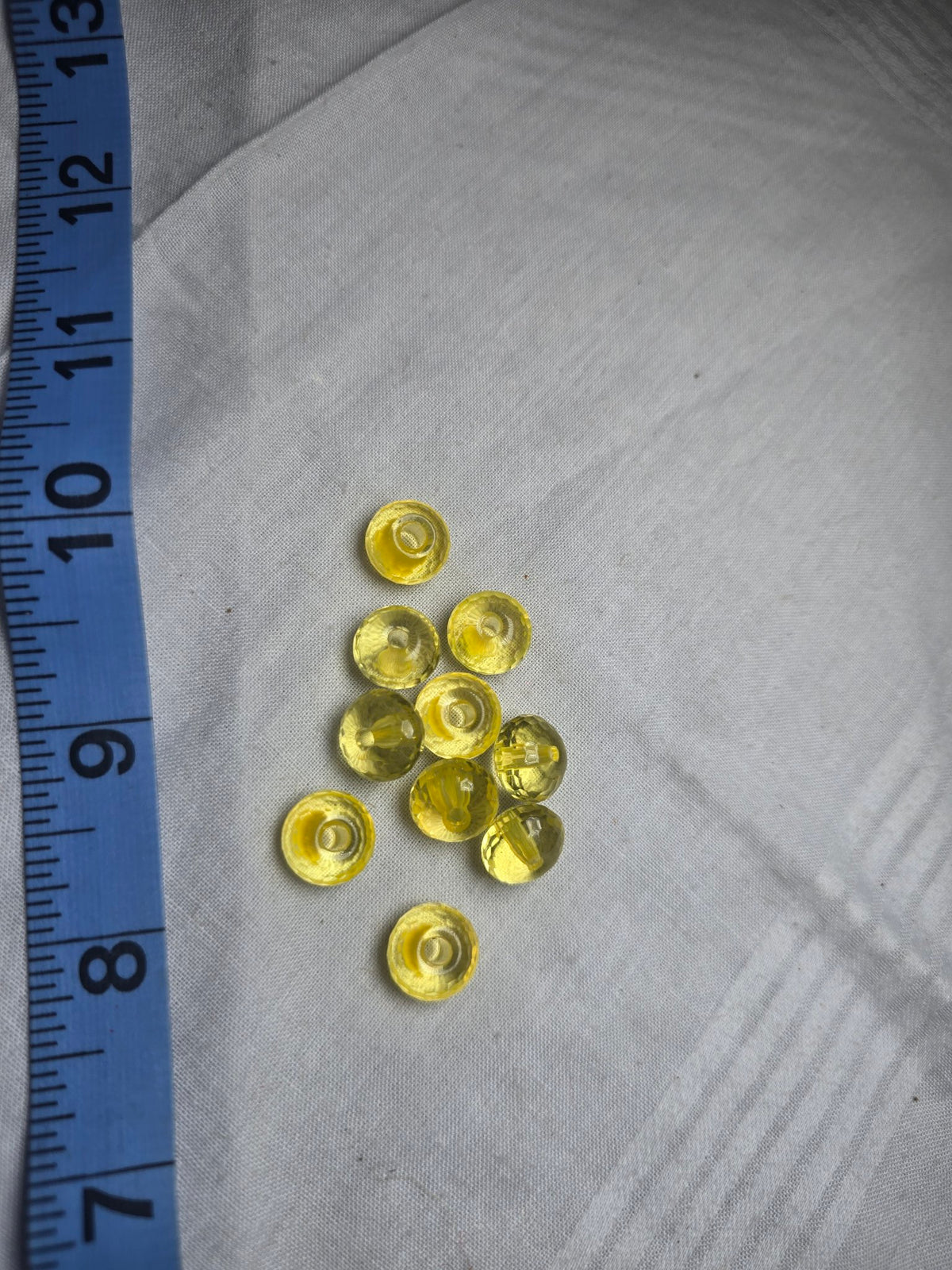 Ten yellow translucent crystal rondelle beads with ruler for scale