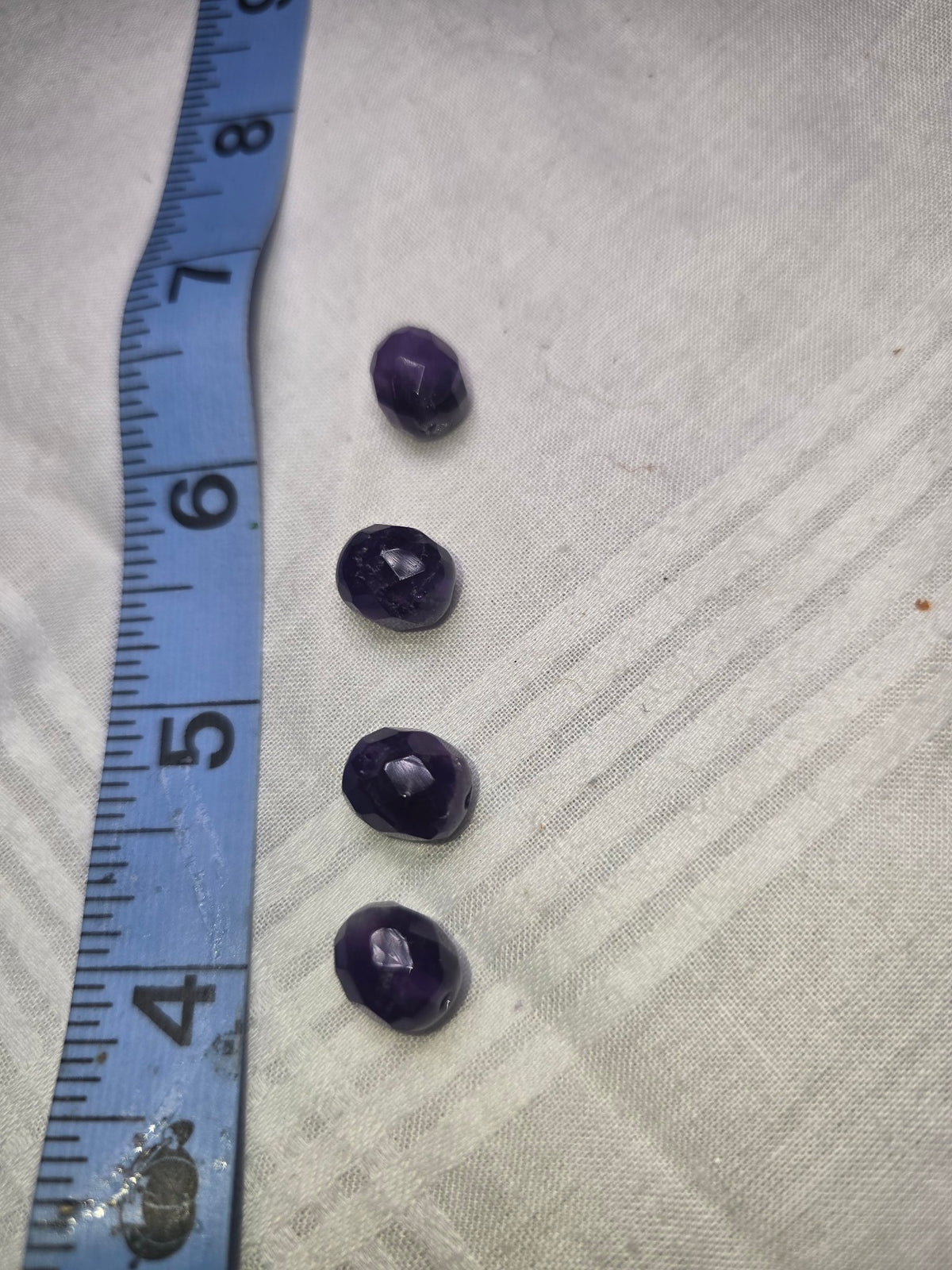 Four deep purple faceted beads with ruler for scale