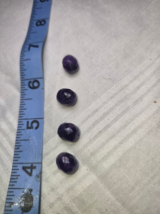 Four deep purple faceted beads with ruler for scale