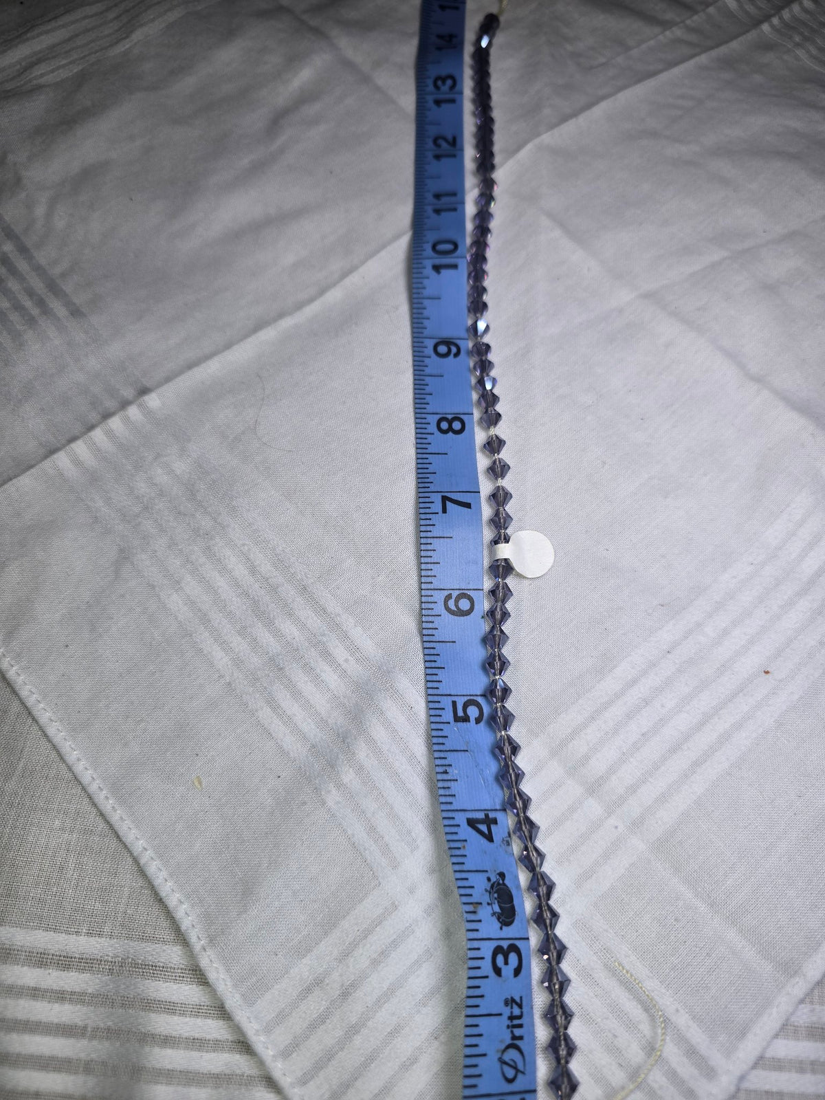 Dark purple crystal bicone bead strand with ruler for scale