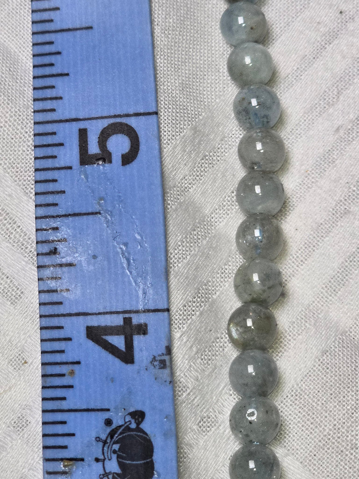 Closeup of aquamarine round beads with ruler