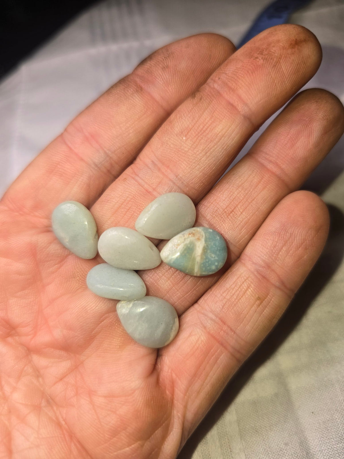 Pale blue teardrop beads held in hand