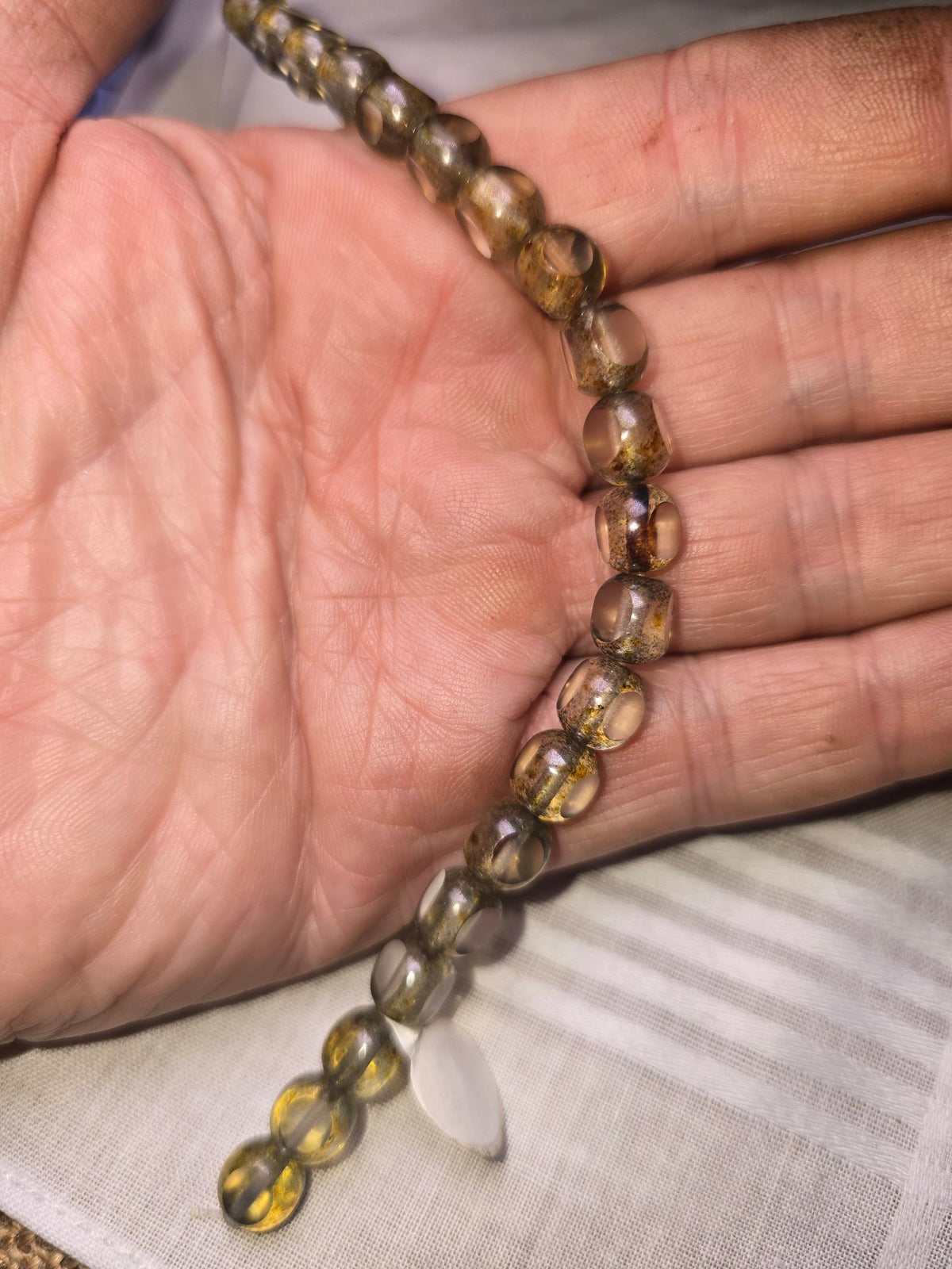 Translucent grey gold round beads in hand