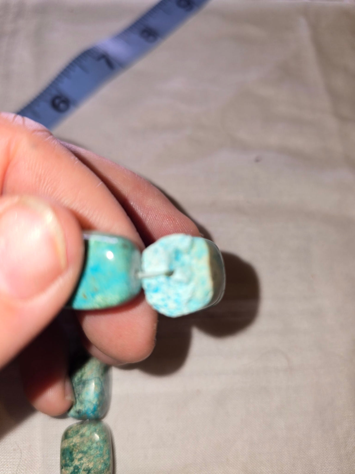 Turquoise-look barrel bead strand hand closeup